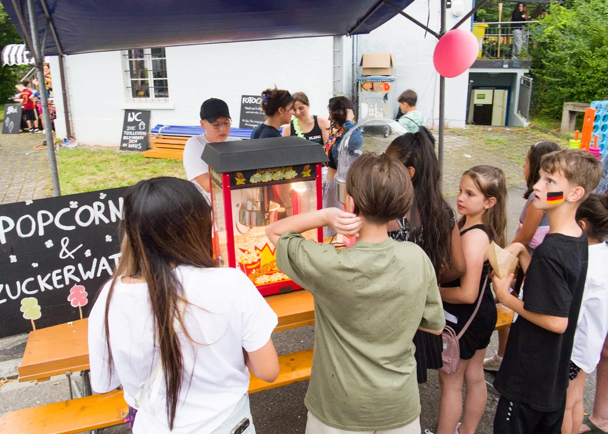 Kinder stehen vor einen Popcornstand.
